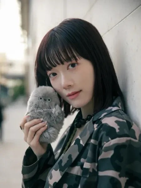 Woman holding a gray plush companion against her cheek